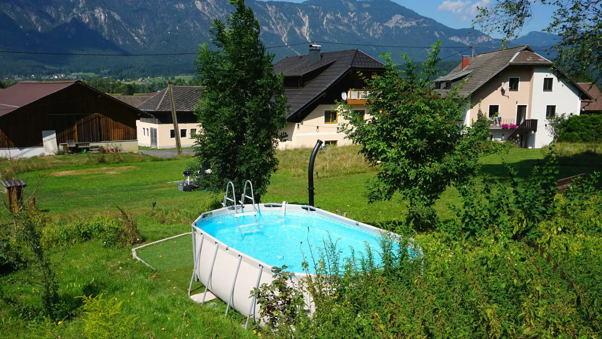 Aufstellpool im Garten, dahinter Häuser und die Berge des Gailtals
