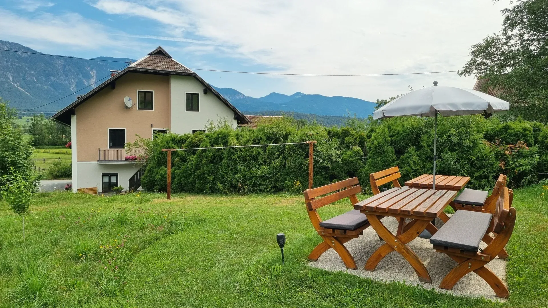 Haus Nampolach mit Garten, Holz-Sitzgruppe und Sonnenschirm vor Bergkulisse